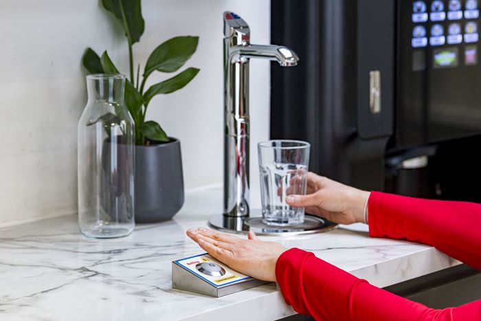  A woman using an accessible tap to pour water into a glass.
