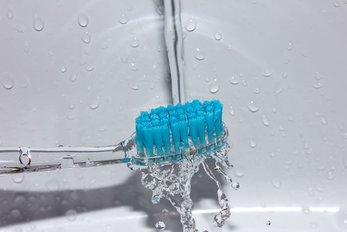 Blue toothbrush held under running water