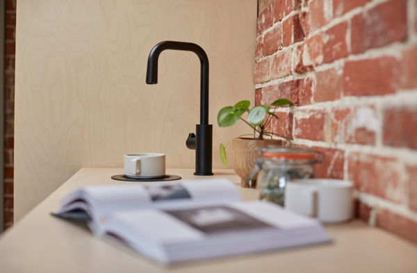 Oak kitchen countertop with a book, plant, and matte black Zip HydroTap. 